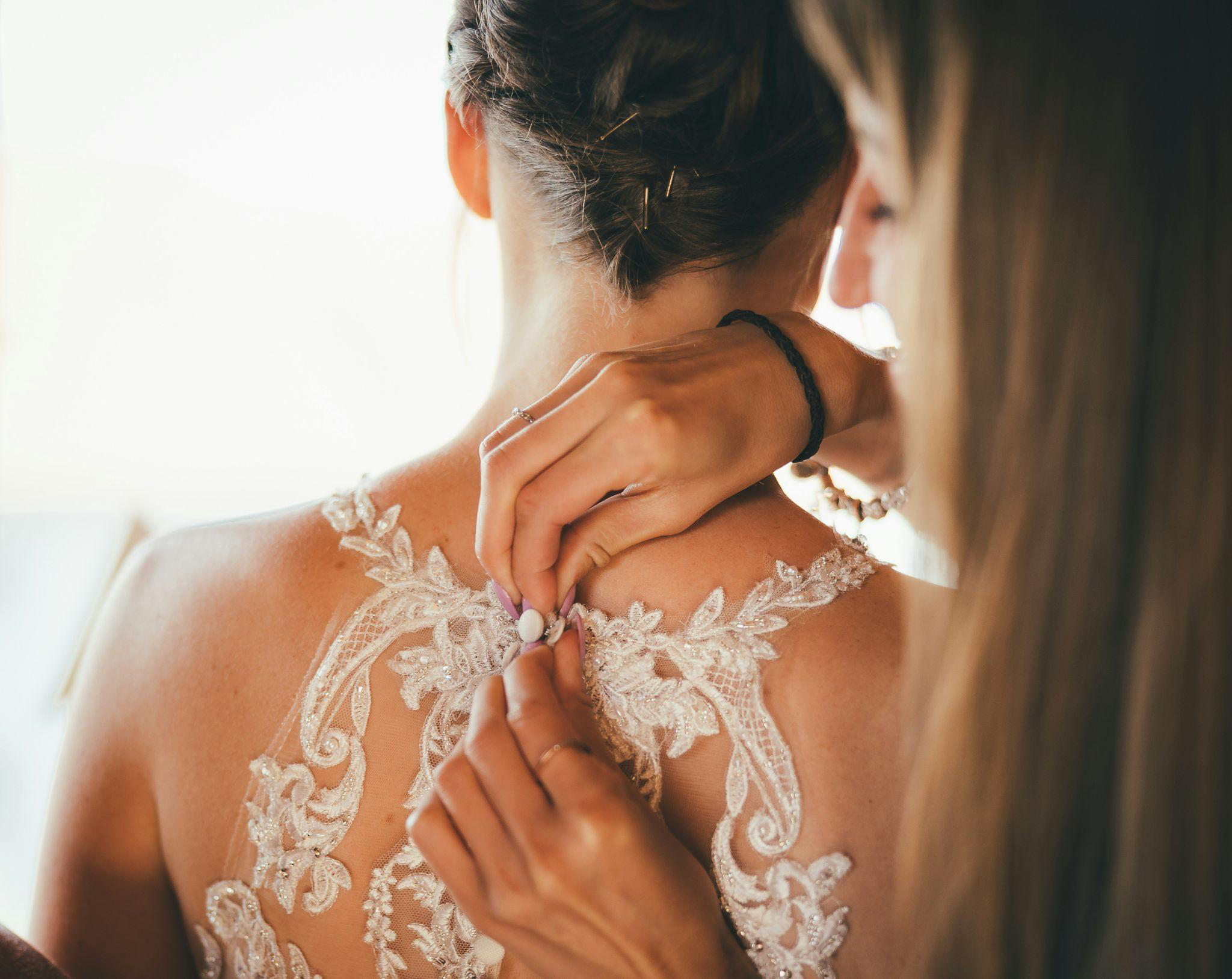 a bride getting her wedding dress buttoned during an appointment