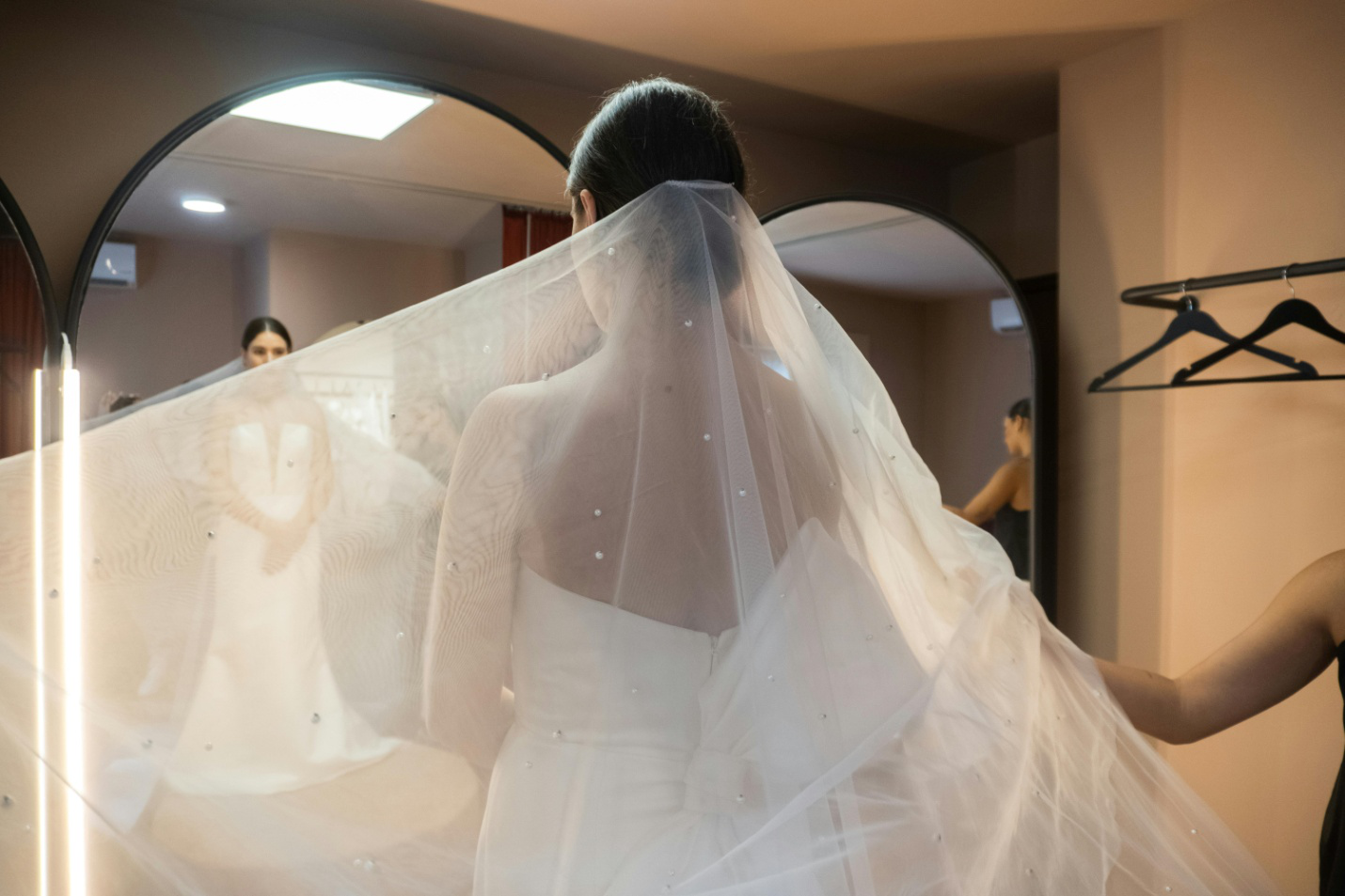 a bride looking at her reflection wearing a wedding dress